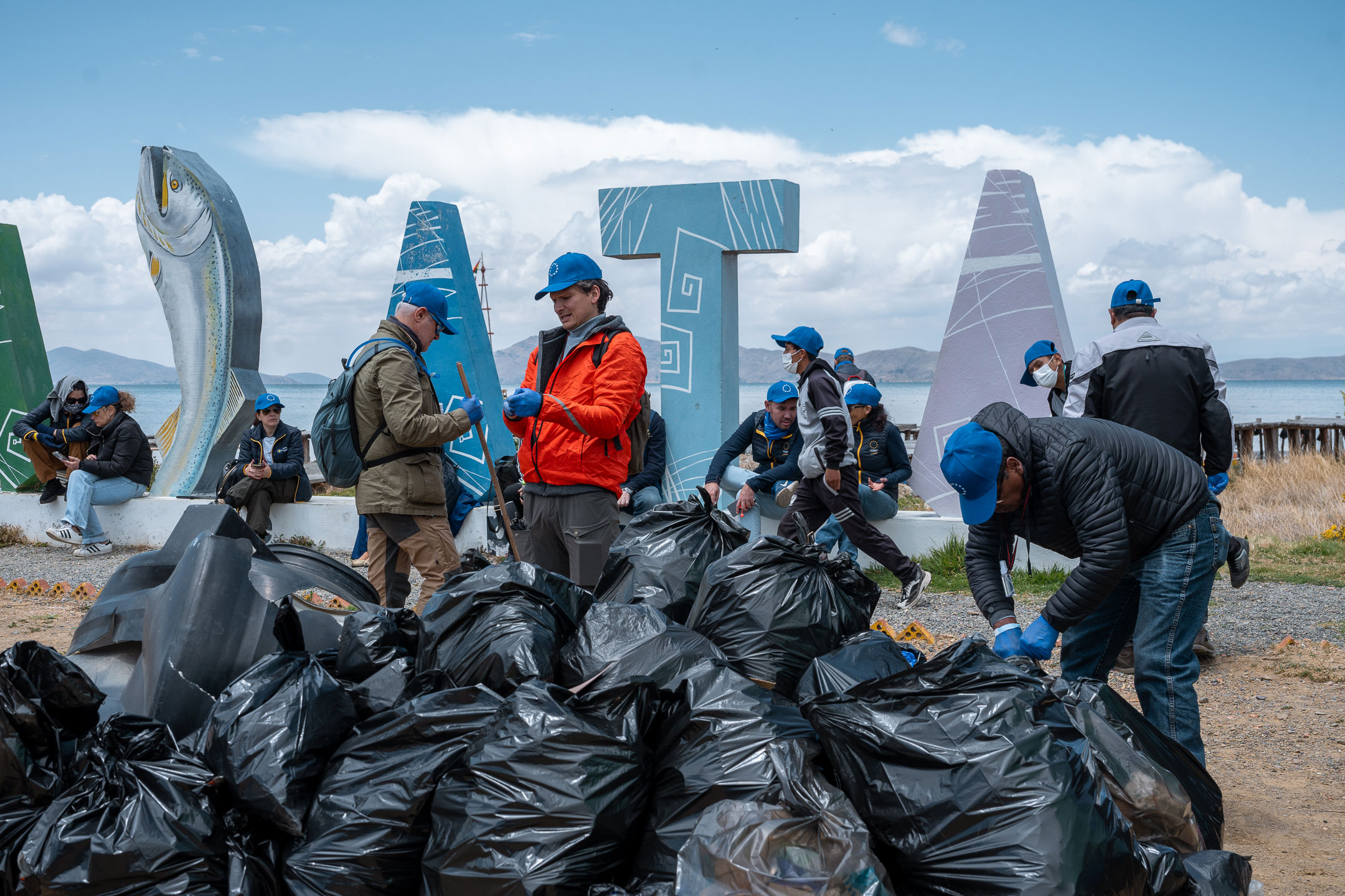 2024 EUBeachCleanup Huatajata, Bolivia, people and several filled black rubbish bags