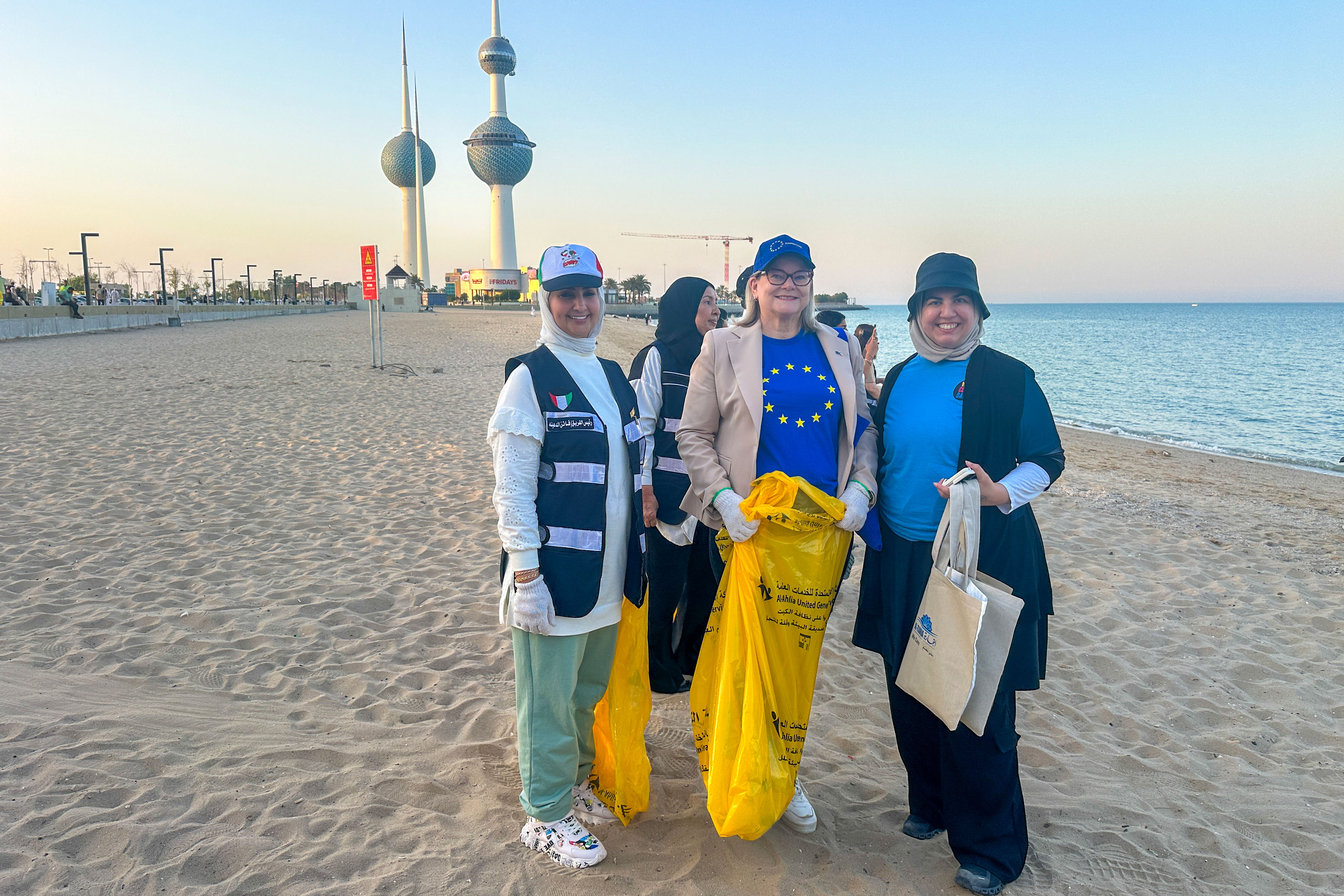 2024 EUBeachCleanup in Kuwait, 3 women on a beach with a yellow plastic bag