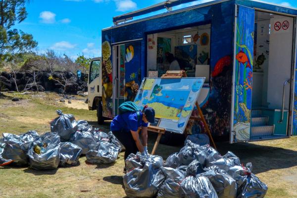 2024 EUBeachCleanup in Mauritius, one person in front of a truck and many grey plastic bags filled with rubbish